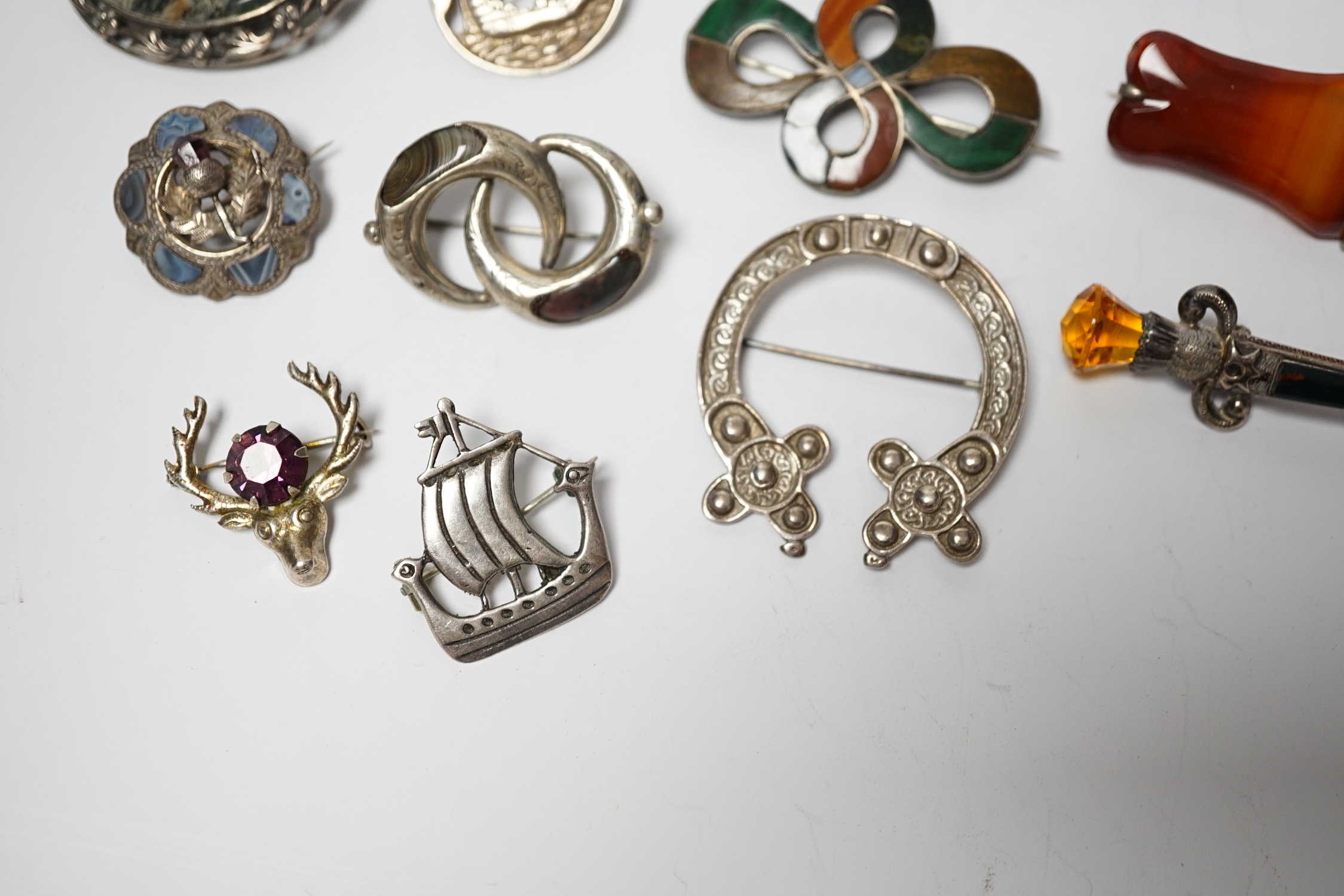 A small collection of mainly silver, sterling and white metal jewellery including Celtic brooches, Iona ship brooch, a Scottish hardstone set bugle brooch and other moss agate set and banded agate set items, largest broo